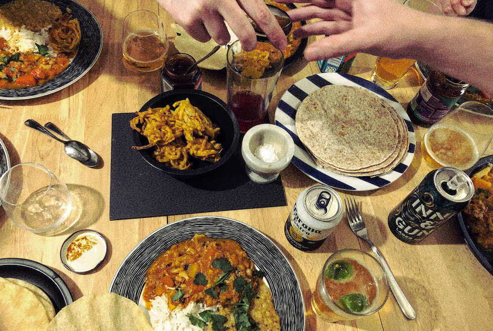 share food | 7 Tips for Creative Block | Image of hands reaching across table of food