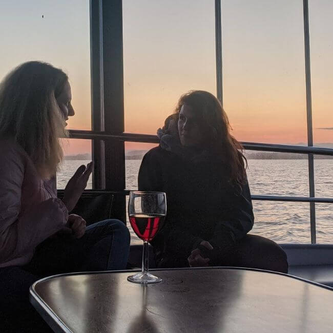 2 non native speakers talking in English with girls on boat talking with wine and sunset