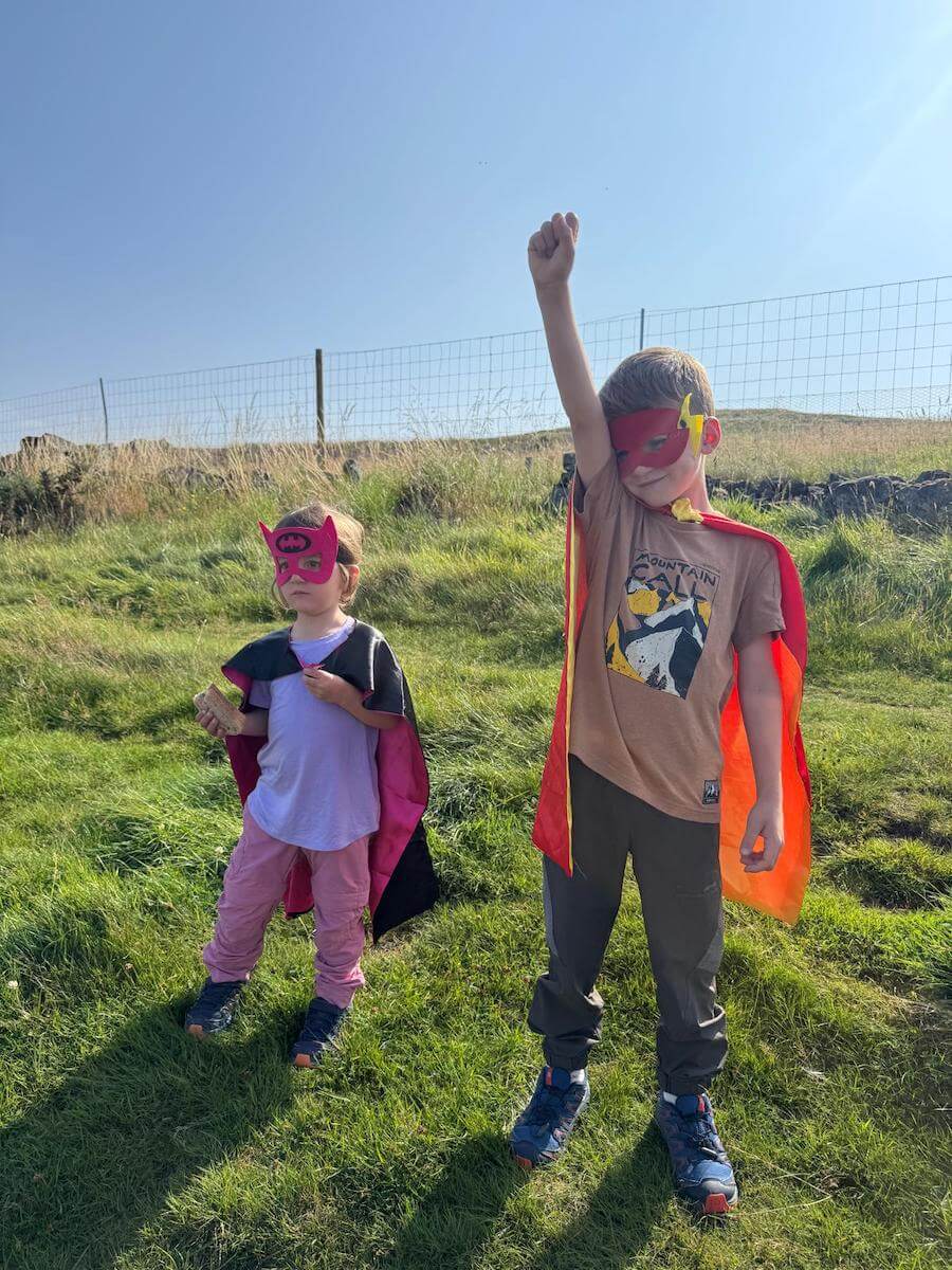 Kids dressed as superheroes climbing the hill Dumyat as part of family english holidya
