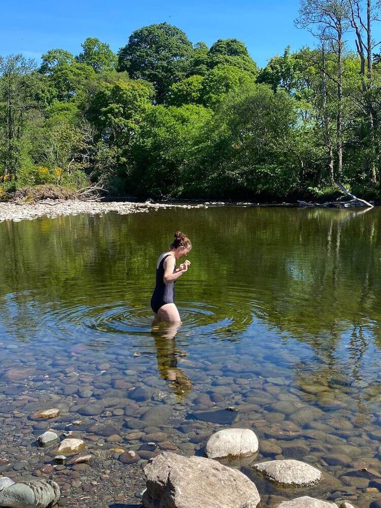Ruth Pringle entering a clear wild swimming pool during an English coaching holiday in Scotland