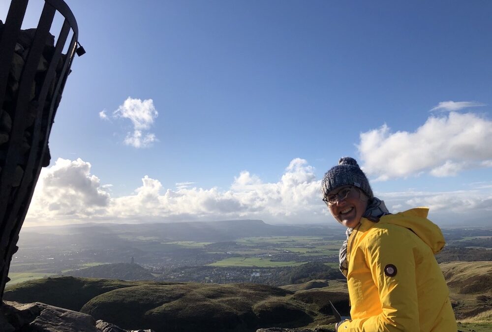 Girl on top of Dumyat hill overlooking Stirling and surrounding landscape
