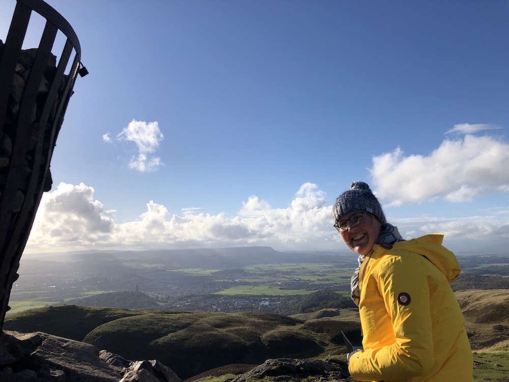 Girl on top of Dumyat hill overlooking Stirling and surrounding landscape