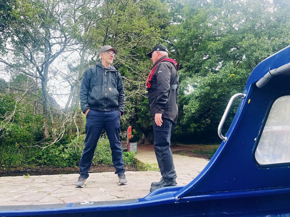 Conversation on the jetty at Inchmaholme Island in the Trossachs. Ferry boat in foreground.