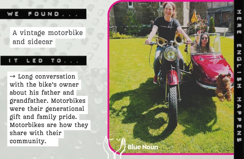 Blue Noun language guest sitting in the sidecar of a vintage motorbike after a conversation with its owner about motorbikes and family history in Scotland.